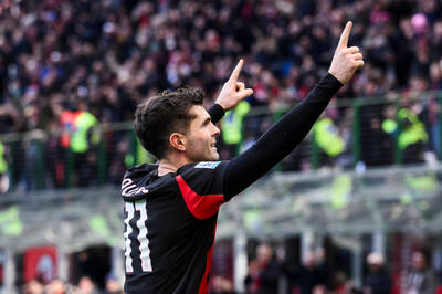 Christian Pulisic pointing with both hands raised while celebrating a goal for AC Milan.