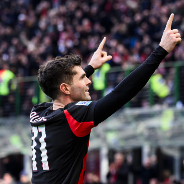 Christian Pulisic pointing with both hands raised while celebrating a goal for AC Milan.